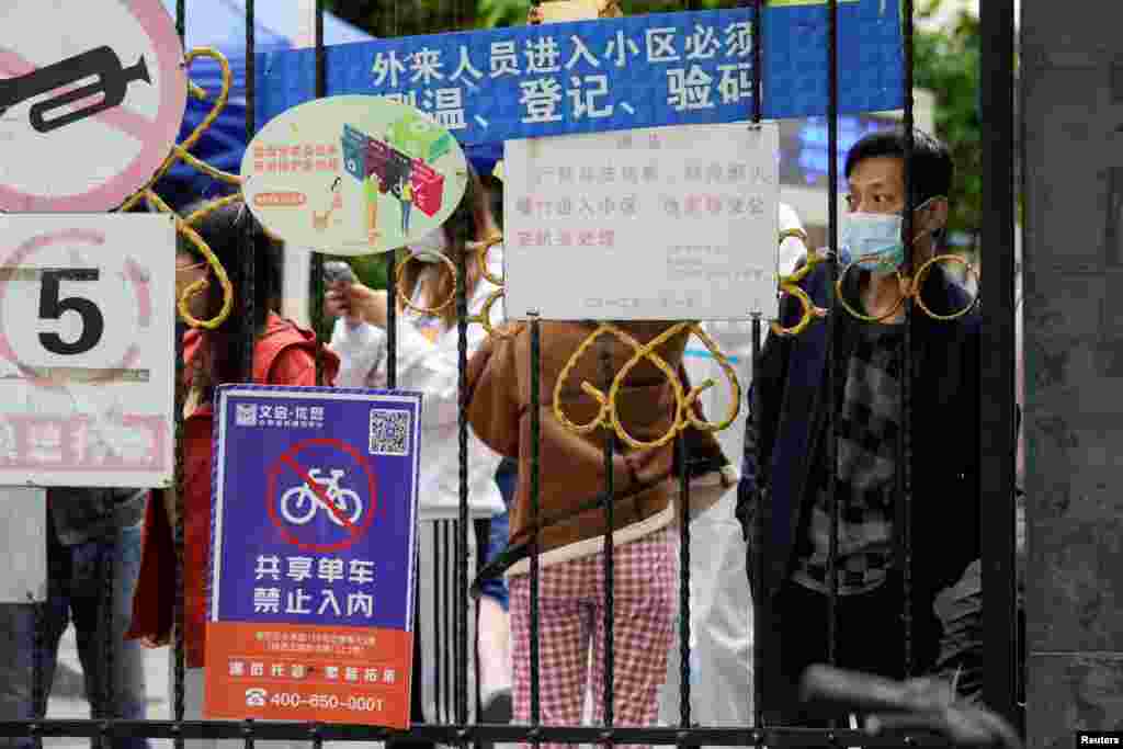 Një tjetër pamje e banorëve të Shangait duke pritur shpërndarjen e ushqimit pas portës së mbyllur që bllokon hyrjen në zonën e banimit.