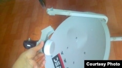 Жительница Жанаозена Айгул Болекбайкызы показывает разбитую спутниковую антенну. Жанаозен, 11 июня 2012 года.     