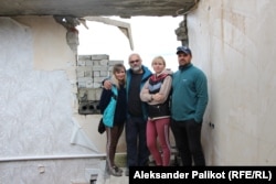 Maryna Snizhynska dhe familjarët e saj, dalin në fotografi pranë shtëpisë së tyre të shkatërruar në Dolina. 5 tetor 2022.