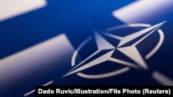 Лягатып NATO на фоне сьцягу Фінляндыі 