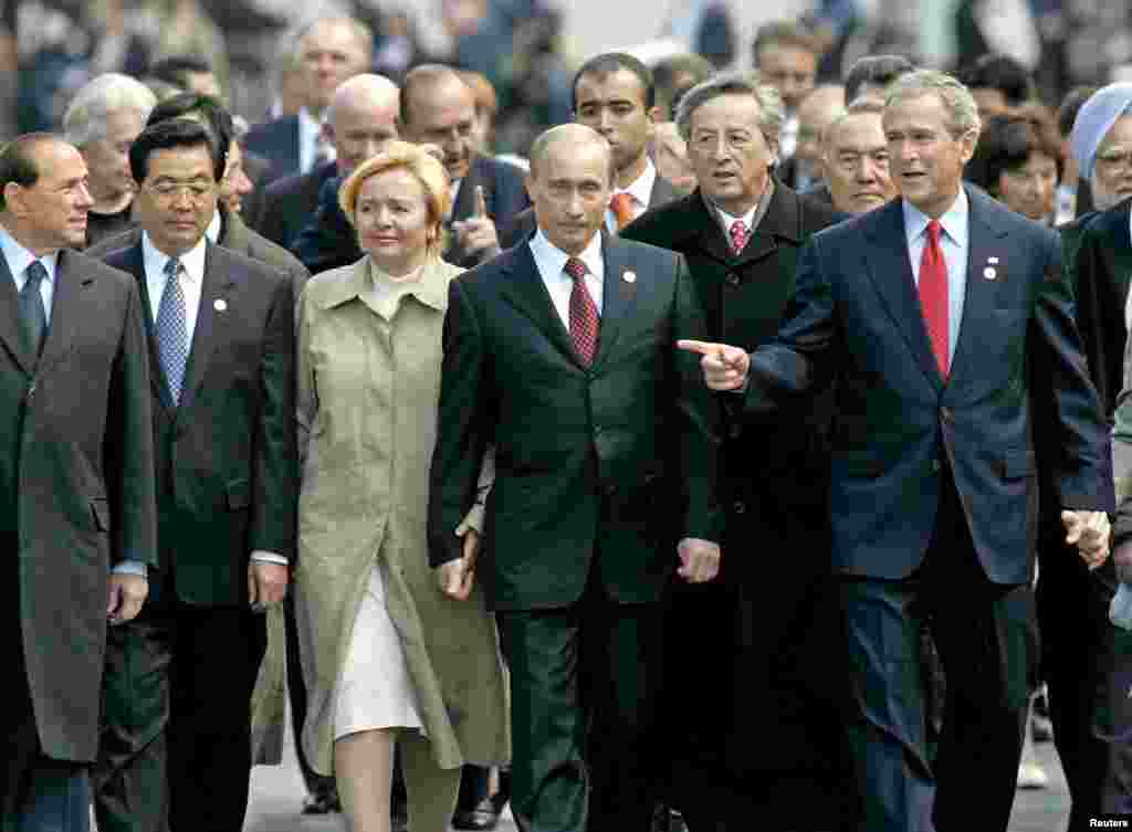 Прэм'ер-міністар Італіі Сільвіё Берлусконі, лідэр Кітаю Ху Дзінь Тао, прэзыдэнт Расеі Пуцін з жонкай Людмілай, кіраўнік Эўракамісіі Жан-Клёд Юнкер і прэзыдэнт ЗША Джордж Буш-малодшы ідуць разам паблізу Крамля ў Маскве пасьля ўдзелу ў цырымоніі памяці ахвяр Другой усясьветнай вайны на Чырвонай плошчы 9 траўня 2005 году.