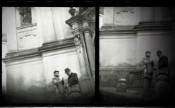 Doi bărbați, care discută în curtea unei biserici, lângă Castelul din Praga.