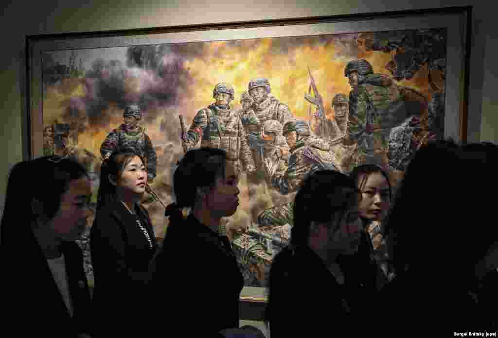 Түндүк Корея өлкөсүнөн барган туристтер "Мекендин ар-намысы үчүн күрөшкөн баатырлар" деген сүрөттүн жанында. Сүрөттүн сол жактагы үстүңкү бурчунан православ чиркөөсүн көрүүгө болот.