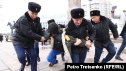 Полицейские задерживают и ведут к автозаку активиста на площади Республики в Алматы. 20 ноября 2022 года