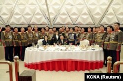 Kim Jong-un, soția sa Ri Sol-ju (stânga) și fiica lor Kim Ju-ae (în picioare lângă tatăl său, în centru) la masă, înconjurați de comandanți militari, la banchetul organizat cu ocazia celei de-a 75-a aniversări a Armatei Populare Coreene, Phenian, 7 februarie 2023.