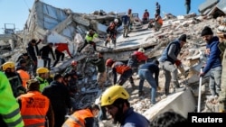 Люди работают на месте обрушившегося здания, поиски выживших продолжаются после смертельного землетрясения в Хатае, Турция, 9 февраля 2023 года.