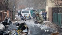 Украінскі салдат разглядае аскепкі зьбітага самалёта ў Кіеве 25 лютага