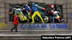 Një person kalon pranë një monumenti të ushtrisë sovjetike, të ngjyrosur me ngjyrat e flamurit të Ukrainës, poshtë së cilit është shkruar "Lavdi Ukrainës". Sofje, 28 shkurt 2022.