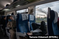 Pasagerii dorm în timp ce soarele răsare și trenul se apropie de Kiev.