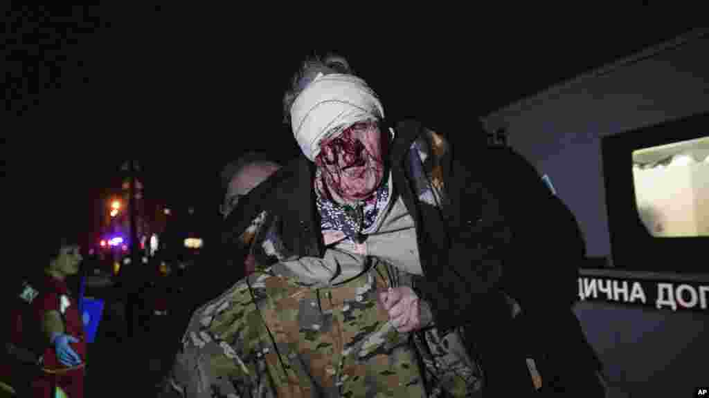Një ushtar ukrainas e bart në krah një grua të plagosur duke e nxjerrë nga shtëpia e saj, e cila u godit nga sulmi rus në Kiev.