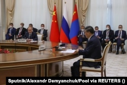 Si Jinping (sagda öňde) we Wladimir Putin (çepde) sentýabr aýynda Özbegistanda geçen Şanhaý hyzmatdaşlyk guramasynyň sammitiniň çäklerinde geçirilen duşuşykda çykyş edýärler.