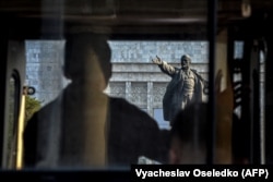 Un protestatar privește o statuie a lui Lenin în Bișkek, în 2021.