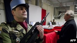 A French soldier stands guard as French Defense Minister France Gerard Longuet (right) pays his respects in front of the coffins of the four French soldiers killed in Afghanistan during a ceremony at Kabul Airport on January 21.