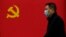 Чоловік у масці на тлі прапора Комуністичної партії Китаю, Ухань, 31 березня 2020 року