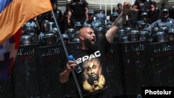 Armenia - An opposition supporter waves a Karabakh flag outside a goverment building guarded by riot police, May 31, 2022.