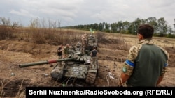 უკრაინელები ათვალიერებენ მიტოვებულ რუსულ ტანკს ხარკოვის ოლქში, 2022 წლის 10 სექტემბერს