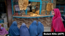 بحرانی اقتصادی و بشری در افغانستان- شماری از زنان در مقابل یک خبازی در شهر کابل نشسته اند تا نان خشک رایگان به دست آورند