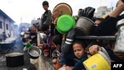 Copiii palestinieni așteaptă să colecteze alimente într-un punct de donații dintr-o tabără de refugiați din Rafah. 23 decembrie 2023