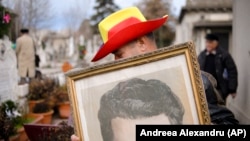 Un bărbat ține portretul dictatorului comunist român Nicolae Ceaușescu, în timp ce nostalgicii se adună la mormântul lui din București, la 30 de ani de la Revoluția din 1989 și de la executarea cuplului dictatorial în ziua de Crăciun. 