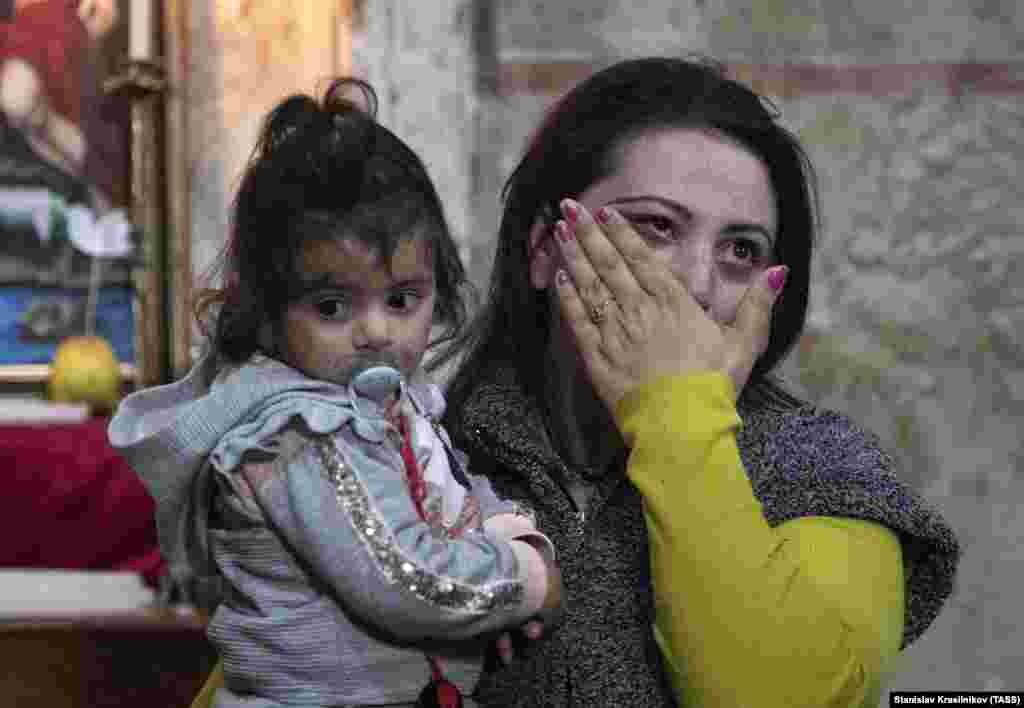 A woman wipes away tears as she walks inside the monastery with her daughter.
