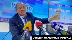 Министр здравоохранения Алымкадыр Бейшеналиев на пресс-конференции с бутылкой с отваром аконита. 16 апреля 2021 года.