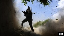 An Afghan Army soldier uses his weapon among smoke and rubble after an attack by IS militants in Nangarhar on May 21.