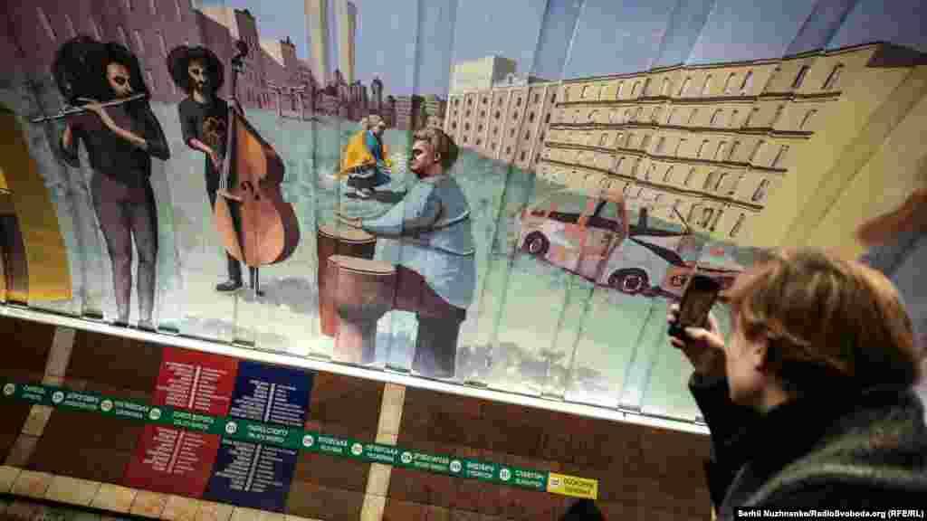 Чоловік фотографує мурал бразильського художника Apollo Tores, присвячений музиці, яка об'єднує різні сторони конфлікту, як це було під час Майдану