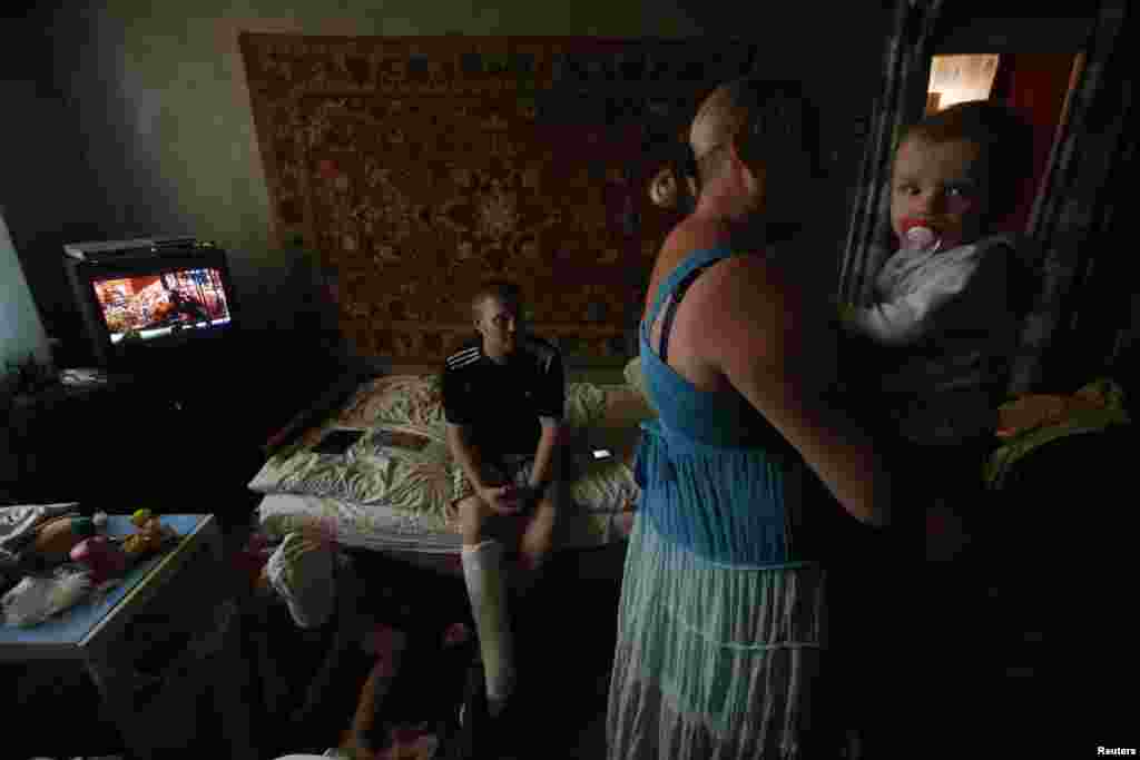 Anya Savchenko (right), Sergei Smirnov, &nbsp;and their 9-month-old baby, who have fled fighting in Slovyansk, stand in their temporary accomodation in the town of Nyzhnya Krynka.