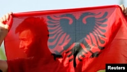 Një djalë duke mbajtur një flamur shqiptar - Fotografi nga arkivi.