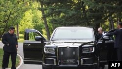 În această fotografie de la piscină distribuită de agenția rusă de stat Sputnik, președintele rus Vladimir Putin îi prezintă liderului nord-coreean Kim Jong-un, la Phenian, pe 19 iunie 2024, o limuzină Aurus.