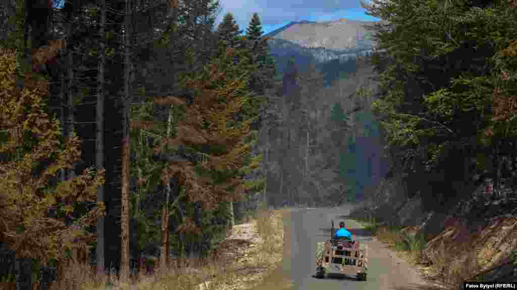 Një banor lokal në Shtupeq kalon me traktor derisa në të dy pjesët e rrugës mali është djegur.&nbsp;