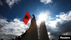 Një djalë duke mbajtur flamurin shqiptar - Fotografi nga arkivi.