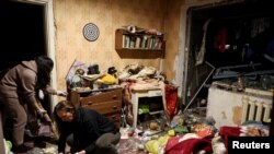 د اوکراين په کريويي ريه کې د اپرېل پر څلورمه د روسيې تر بريد وروسته ځايي کسان کور پاکوي. 