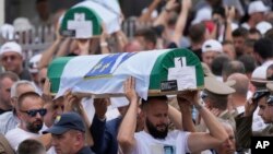 بوسنیايي سړي د ۱۹۹۵ز کال تر نسل وژنې درې لسیزې وروسته د اووه نویو پېژندل شویو د پاتې شونو تابوتونه لېږدوي - د جولای ۱۱مې انځور.