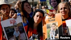 Кфир, Ариэл жана Шири Бибастын сүрөттөрүн кармаган израилдиктер. 1-февраль, 2025-жыл. Тель-Авив.