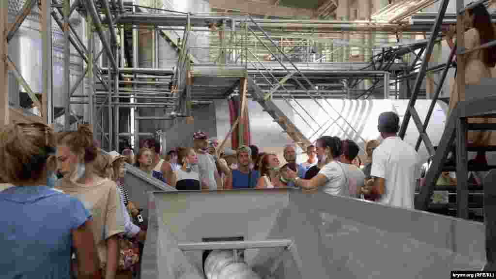 Екскурсійна група на заводі. &nbsp; Екскурсовод розповідає, як отримують ферментоване (червоне і рожеве) вино. Екскурсія для дорослого обійдеться в 400 рублів (150 грн), для дитини &ndash; в 200 рублів (75 грн). Для відвідування закритих цехів обов'язкові маски