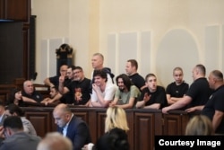 ჯგუფურ მოქმედებაში დამნაშავეებად ცნობილი დემონსტრანტების ერთი ჯგუფი სასამართლო პროცესზე.