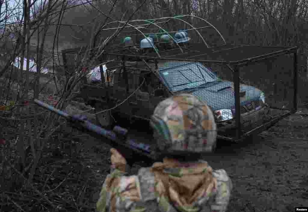 Një ushtar ukrainas kontrollon qiellin për dronë rusë, teksa një makinë niset për një mision luftarak në Kostiantinivka të Ukrainës më 27 nëntor 2025.