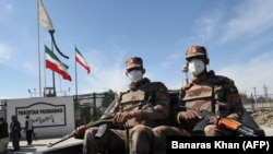 FILE: Pakistani soldiers wearing face masks patrol near the closed Pakistan-Iran border in Taftan in late February.
