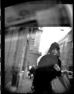 O tânără, în timp ce trece pe lângă un agent sub acoperire care are o cameră foto, în centrul Pragăi.