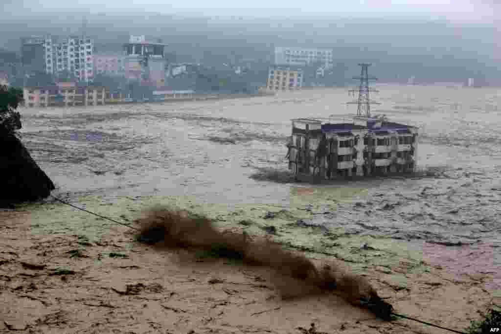 Heavy floodwaters sweep through Beichuan in southwest China's Sichuan Province, as rainstorms sweeping across parts of China have affected millions, causing landslides and disabling transportation. (AFP)