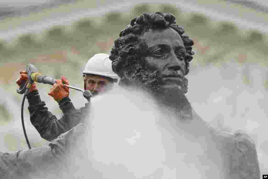 یک کارمند شهرداری در حال تمیز کردن مجسمهٔ آلكساندر پوشکین، شاعر روسیه، در سن پترزبورگ