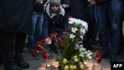 People place flowers and lit candles in memory of victims of the blast in the St. Petersburg subway outside the Sennaya Square station.