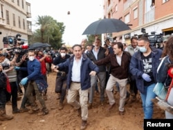 Spaniolii furioși aruncă cu noroi în Regele Felipe al IV-lea (sub umbrelă, în cămașă albastră), Paiporta, 3 noiembrie.