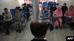Students attend a class bifurcated by a curtain separating males and females at a private university in Kabul on September 7 to follow the Taliban's ruling. 