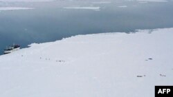 The crew of the Russian fishing boat "Sparta" set out on foot for parachuted supplies as the vessel rests near an Antarctic ice shelf in a December 2011 handout.