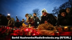 Голодомор құрбандарына арналған ескерткішке гүл мен бидай масағын қойып жатқан адамдар. Украина, 24 қараша 2018 жыл.