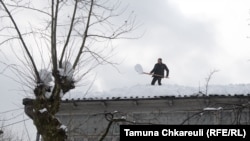 დიდთოვლობა გურიაში - ოზურგეთში კაცი სახლის სახურავს თოვლისგან ასუფთავებს