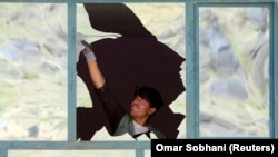FILE: An Afghan man removes broken glass after a suicide bomb blast in Kabul on April 29.