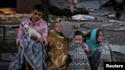 Деца седят близо до жилищна сграда, ударена по време на руската атака с дронове и ракети над украинската столица Киев. 28 август 2025 г.